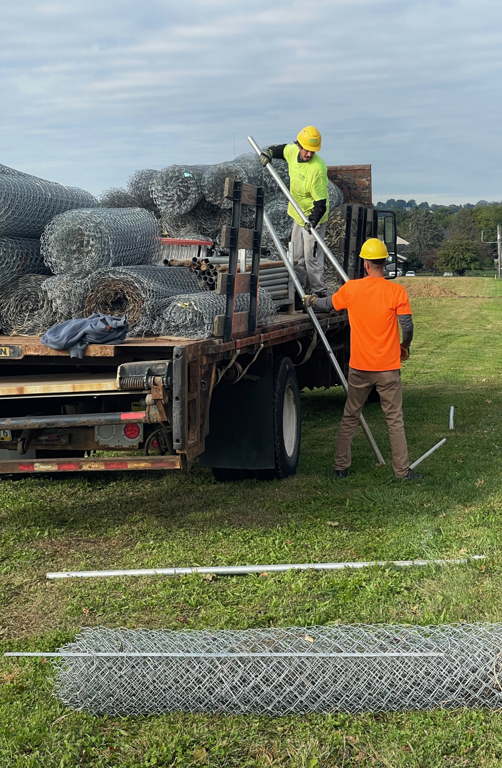 Two workers on Truck unloading rolls of fencing for Driven Fence