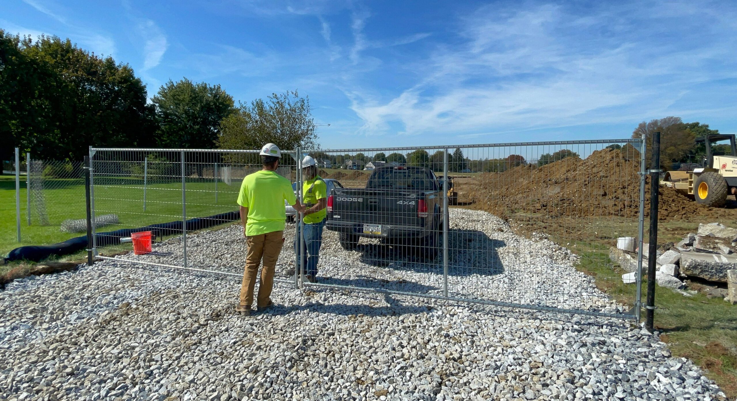 Workers test newly installed swing gates at a construction site