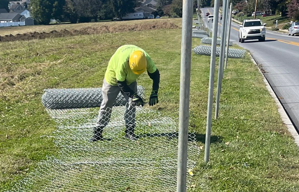 unrolling chain link fence to attach to poles